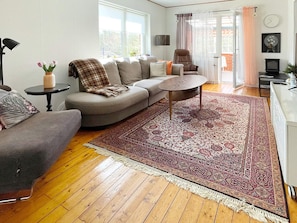 Una sala de estar con sofá, sillón, mesa de centro y alfombra estampada.