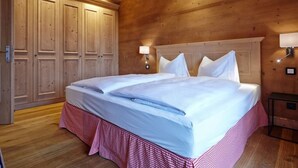 A wooden room with a large bed, two bedside tables, and a wardrobe.