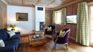 A cozy living room with a fireplace, a sofa, two armchairs, and a coffee table.