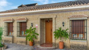 A traditional building with a tiled roof, brick walls, and a tiled entrance. There are two potted plants in front of the entrance. - Belvilla by OYO La Ga1/4ena Vida (Algodonales)