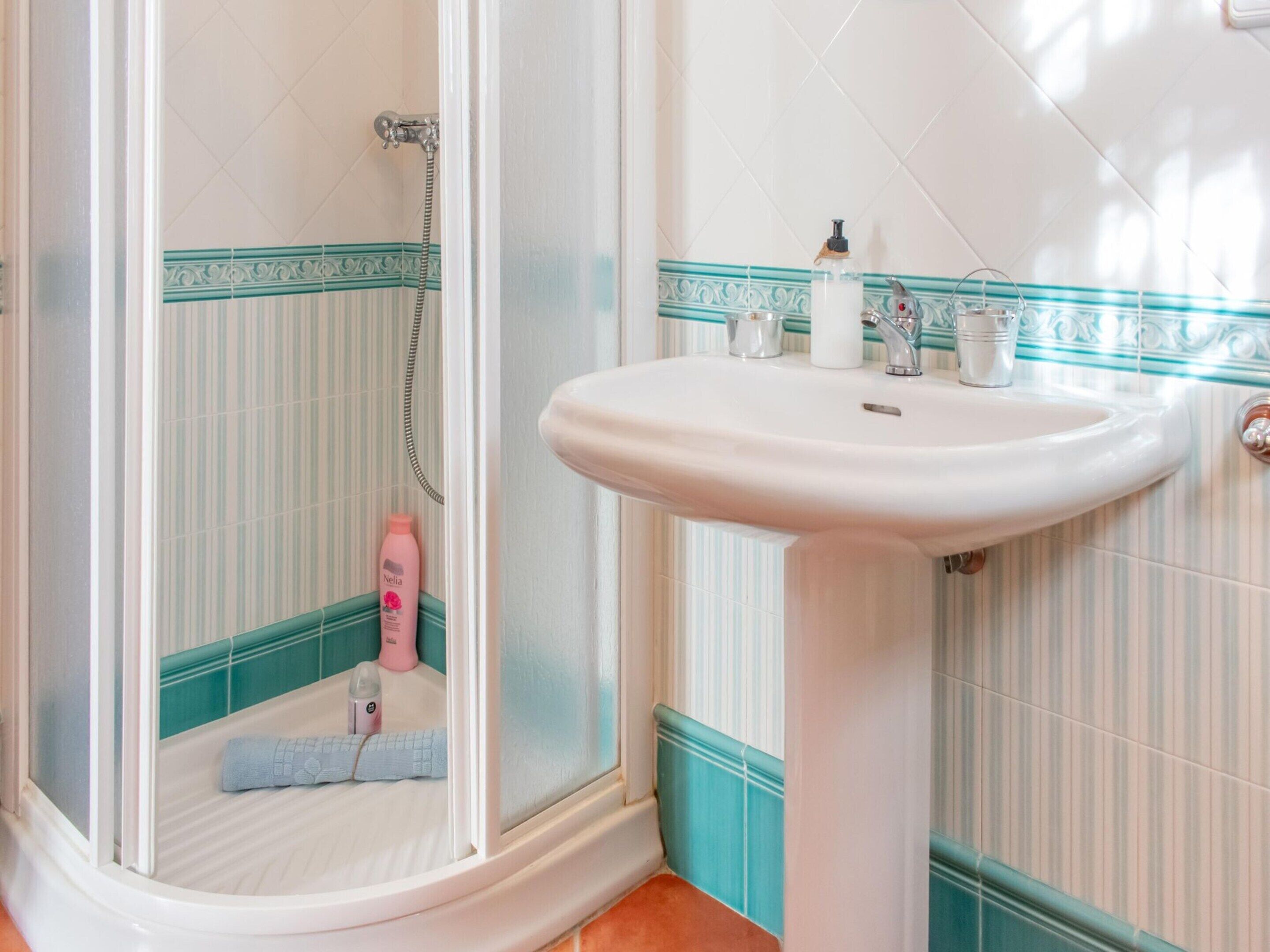 A bathroom with a shower, a sink, and toiletries on the counter.