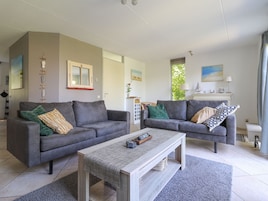 Ein modernes Wohnzimmer mit zwei grauen Sofas, einem Holztisch und einem grauen Teppich.