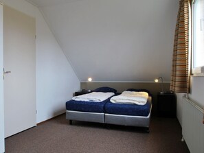 A bedroom with a bed, two bedside tables, a window with curtains, and a radiator. - Nice Holiday Home on the Water in Friesland (Makkum)