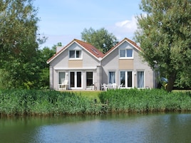 A two-story house with a sloped roof, large windows, and a patio area with outdoor furniture.
