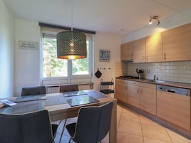 A modern kitchen with wooden cabinets, a gas stove, and a hanging pendant light.