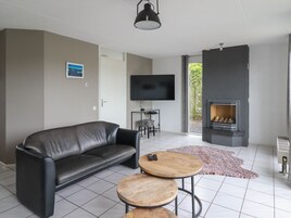 A modern living room with a leather sofa, a TV, a fireplace, and a small wooden table.