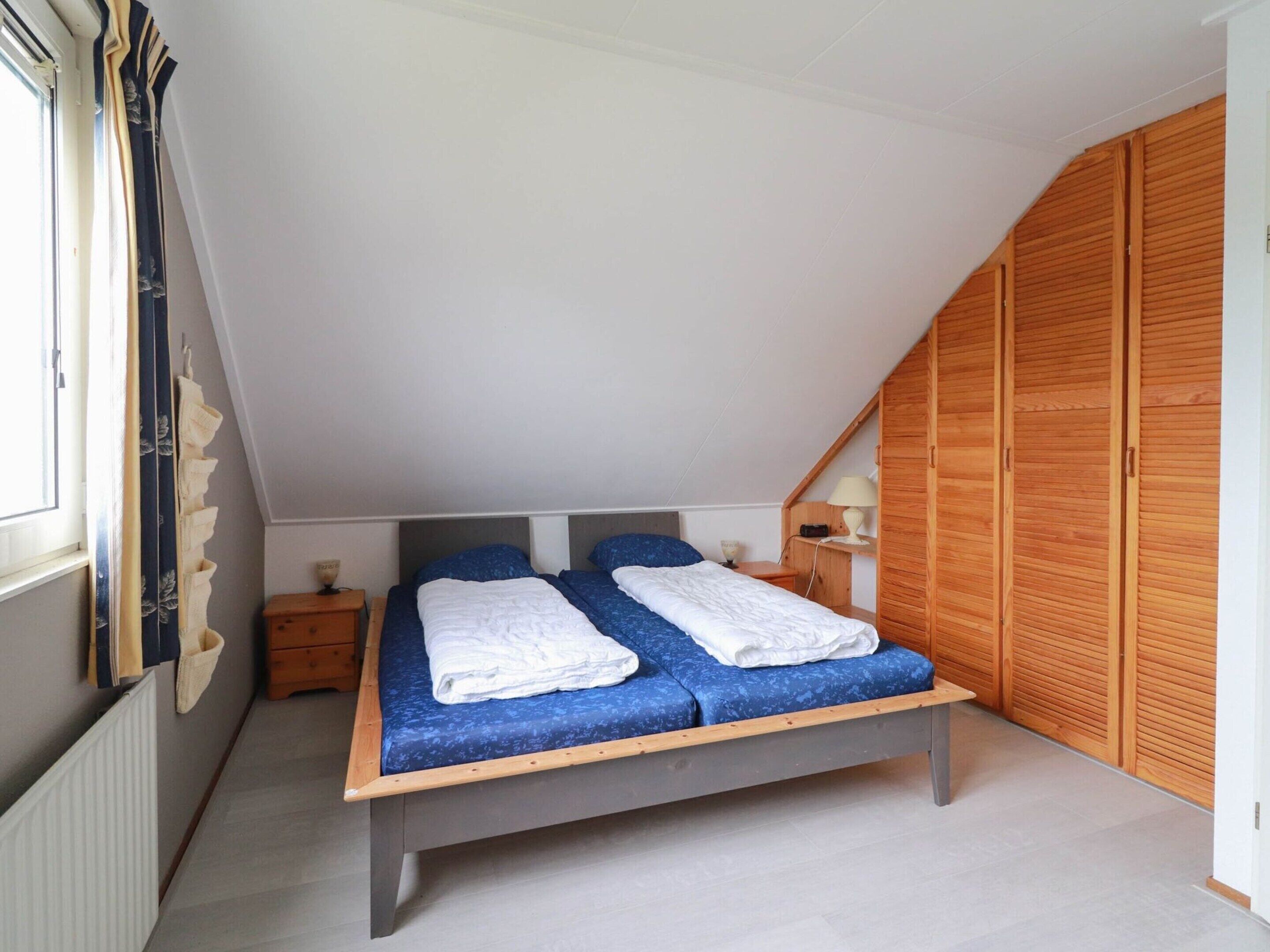 Un dormitorio con cama, armario de madera y ventana.