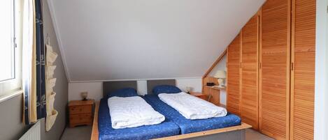 Un dormitorio con cama, armario de madera y ventana.