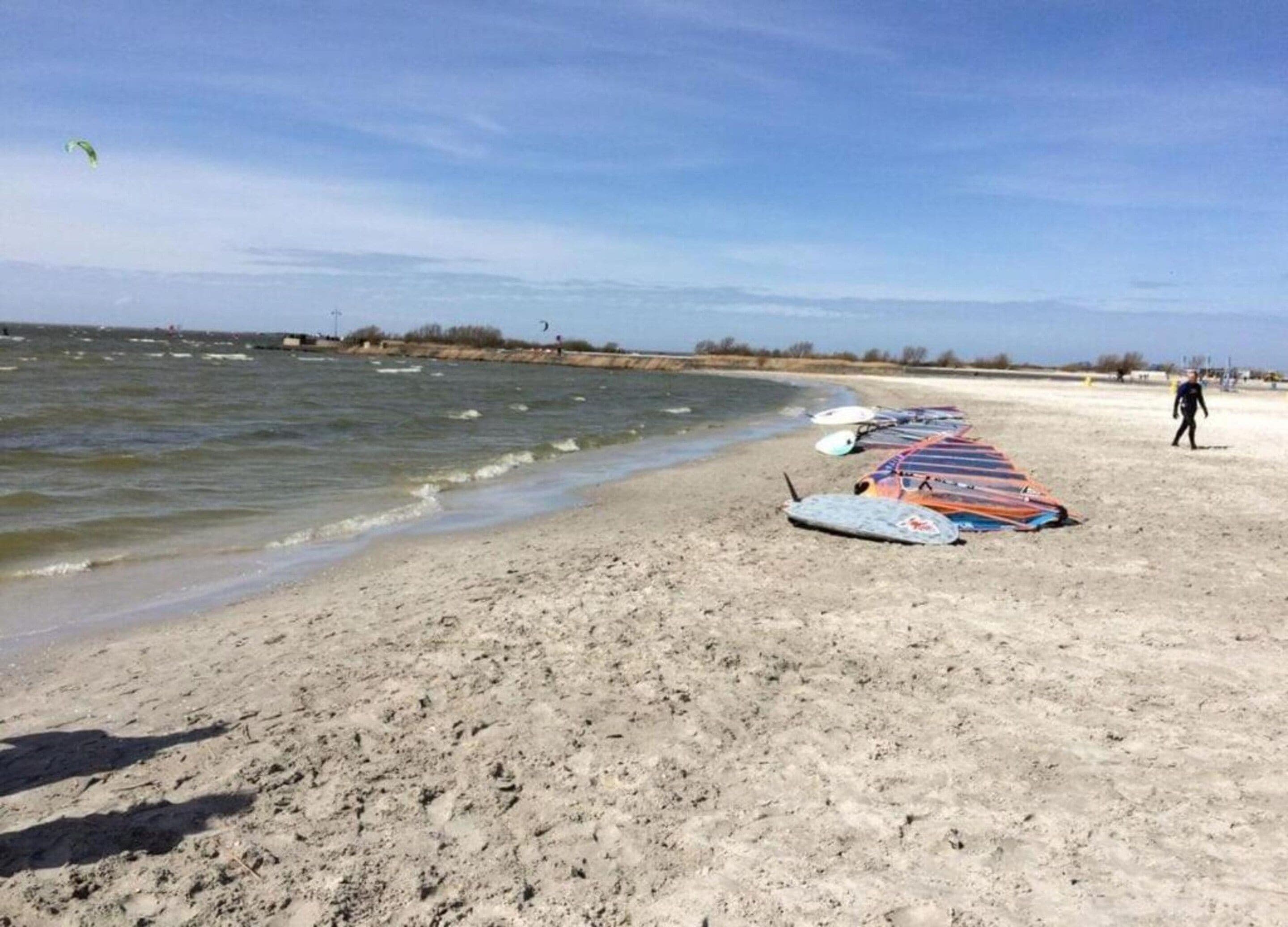 En sandstrand med surfbrädor uppradade och en person som går i fjärran.