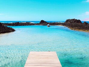 A wooden pier leading into clear turquoise waters with rocky formations on either side. - Orange Apartment in Puerto Rosario With Terrace (Puerto del Rosario)