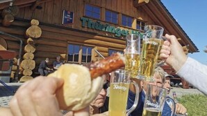 Un edificio de madera con un letrero que dice "Thuninger Lamm". Personas brindan con jarras de cerveza.