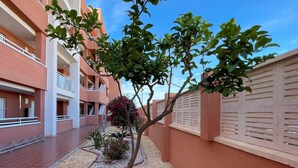 A courtyard with a tree, a small garden, and a building with balconies. - Belvilla by OYO Apartamento Mediterraneo (Roquetas de Mar)