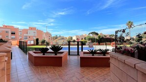 A rooftop terrace with tiled flooring, planters with plants, a pool, and a view of surrounding buildings. - Belvilla by OYO Apartamento Mediterraneo (Roquetas de Mar)