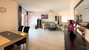 A living room with a sofa, a dining table, and a cabinet. - Belvilla by OYO Apartamento Mediterraneo (Roquetas de Mar)