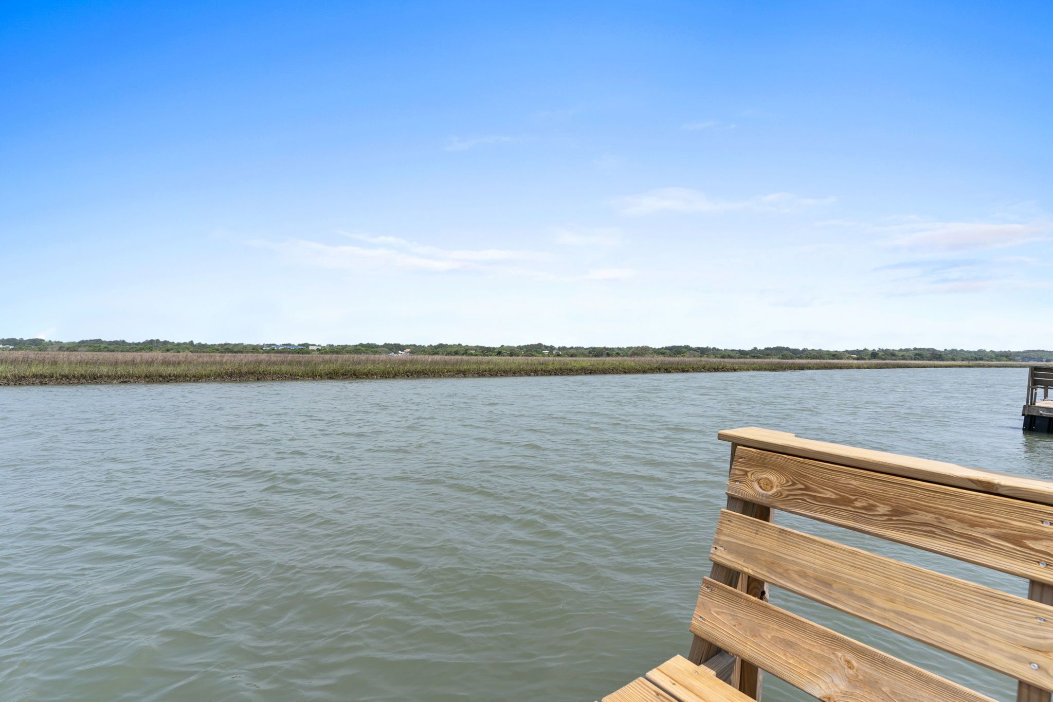 Un muelle de madera que se extiende sobre aguas tranquilas bajo un cielo despejado.