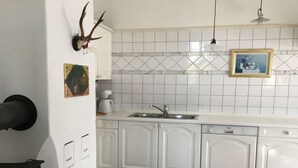 Una cocina con armarios blancos, un lavamanos y salpicadero de azulejos.