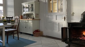Una cocina acogedora con armarios blancos, una mesa de comedor con sillas y una chimenea.
