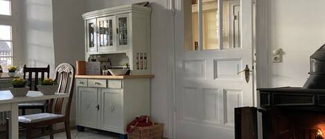 A cozy kitchen with white cabinets, a dining table with chairs, and a fireplace.