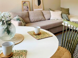 A round dining table with two white ceramic cups and a decorative glass vase with white flowers.