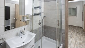 A modern bathroom with a glass shower enclosure, a white sink, and a vanity with storage. - Apartment Mia - Two Bedroom Apartment With Balcony (Split)