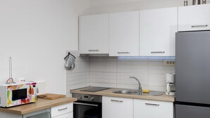A compact kitchen with white cabinets, a stainless steel sink, a microwave, and a built-in oven. - Apartment Mia - Two Bedroom Apartment With Balcony (Split)