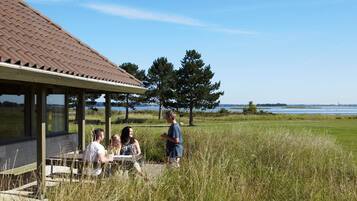 A covered outdoor seating area with a view of a lake and trees.