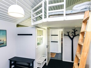 Une chambre de style loft moderne, avec un lit superposé, un bureau et une échelle.