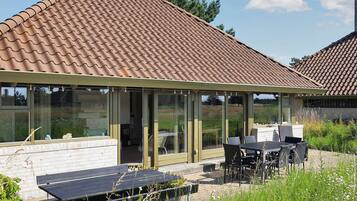 A covered outdoor seating area with a table and chairs, a bench, and a solar panel.