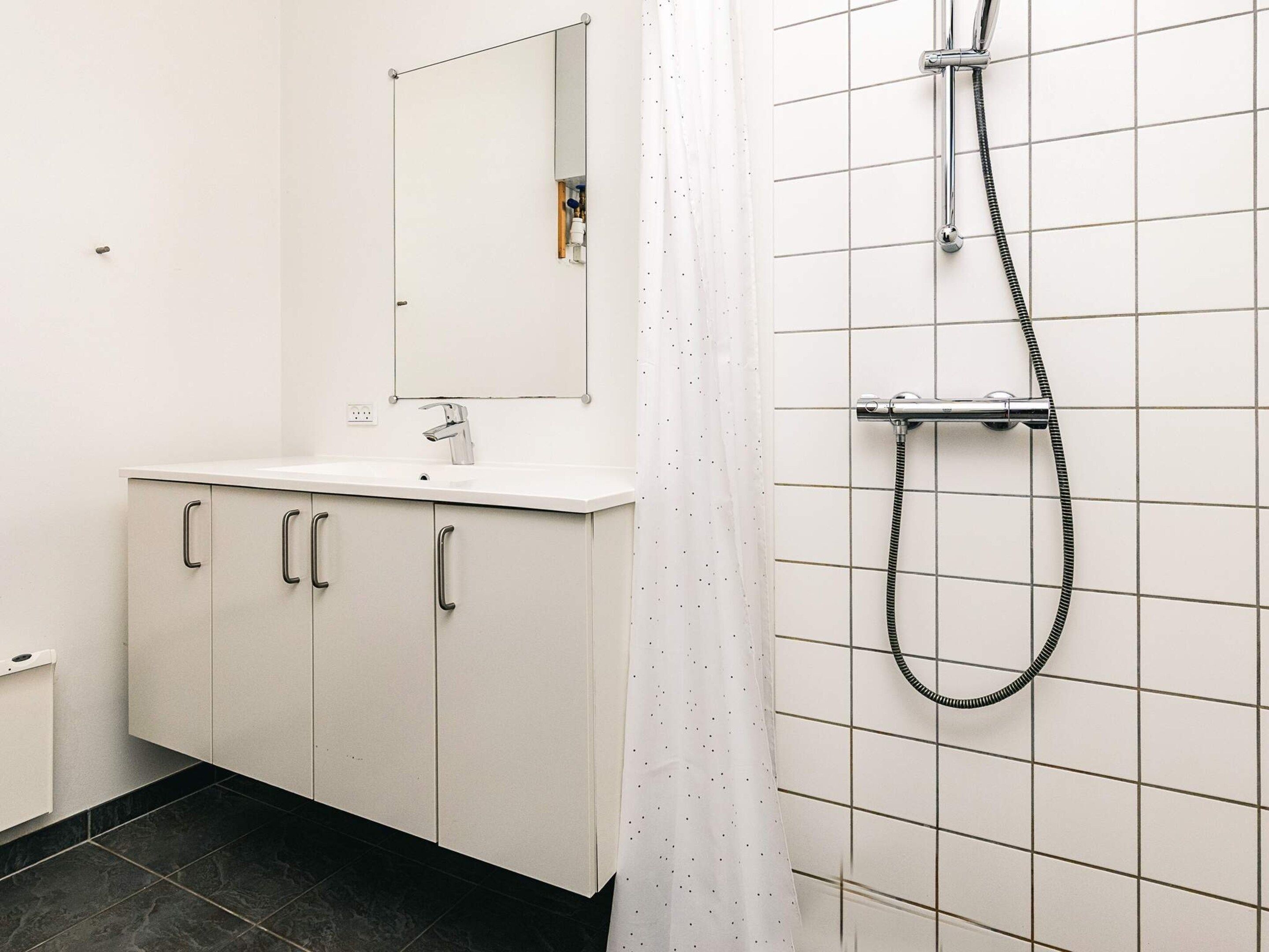 A bathroom with a white sink, mirror, and shower.