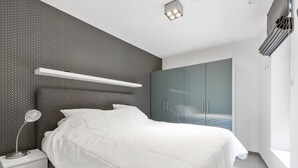 Une chambre à coucher moderne avec un lit, une table de chevet et une armoire.