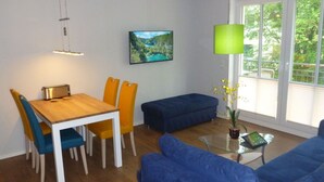 Una sala de estar moderna con una mesa de comedor de madera, un sofá azul y una mesa de centro de vidrio.