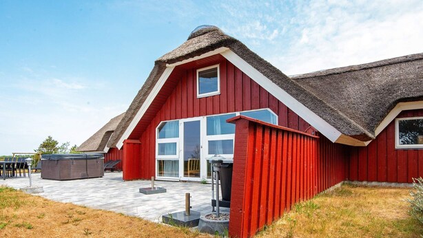 A red barn-style building with a thatched roof, large windows, and a paved patio area.
