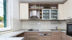 A modern kitchen with wooden cabinets, a stainless steel range hood, a dishwasher, and a built-in oven. - Apartment Villa Rosea (Split)