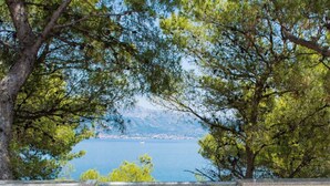A view through a window with a metal railing, overlooking a body of water and distant land. - Apartment Villa Rosea (Split)