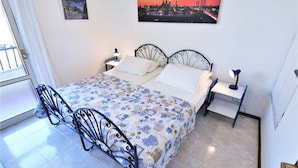 A bedroom with a bed, two nightstands, a desk, and a chair. - Villa in Caorle Near Spiaggia Tartaruga (Caorle)