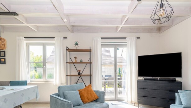Una sala de estar moderna con un sofá, una mesa de comedor, un televisor y una estantería.