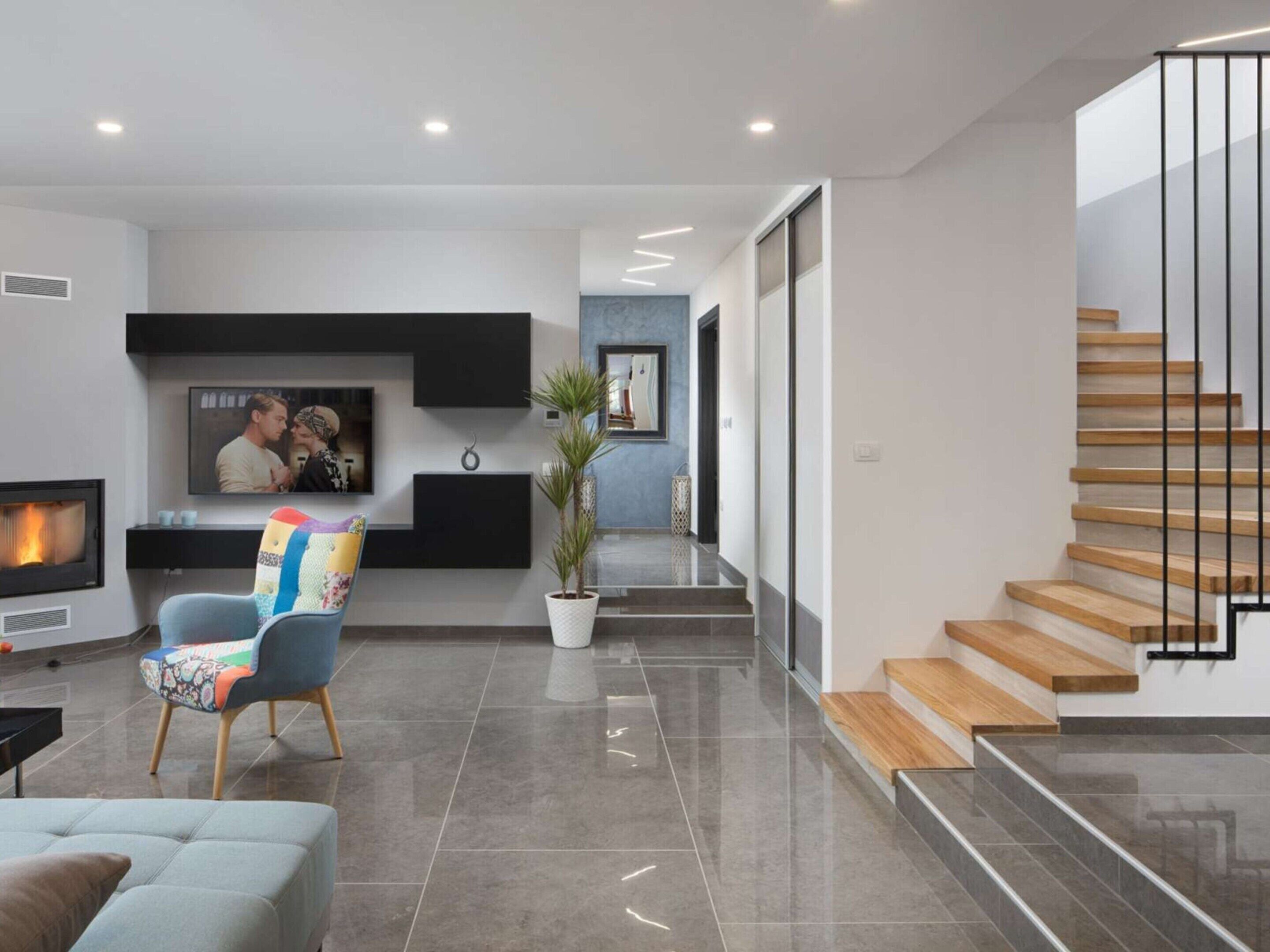 Un salon moderne avec une cheminée, un téléviseur et un escalier.