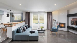 A modern living room with a sofa, a dining area, a fireplace, and a large window. - Villa With Pool Surrounded by Woods in Labin (Labin)