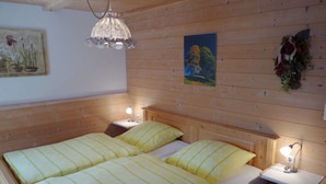 A wooden room with two beds, a nightstand, a wall-mounted lamp, and a painting. - Hirschbichler Modern Retreat (Berchtesgaden)