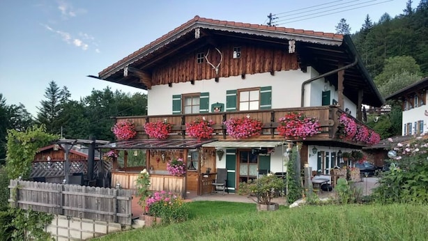A two-story wooden house with a balcony adorned with flowers, a wooden fence, and a grassy yard. - Hirschbichler Modern Retreat (Berchtesgaden)