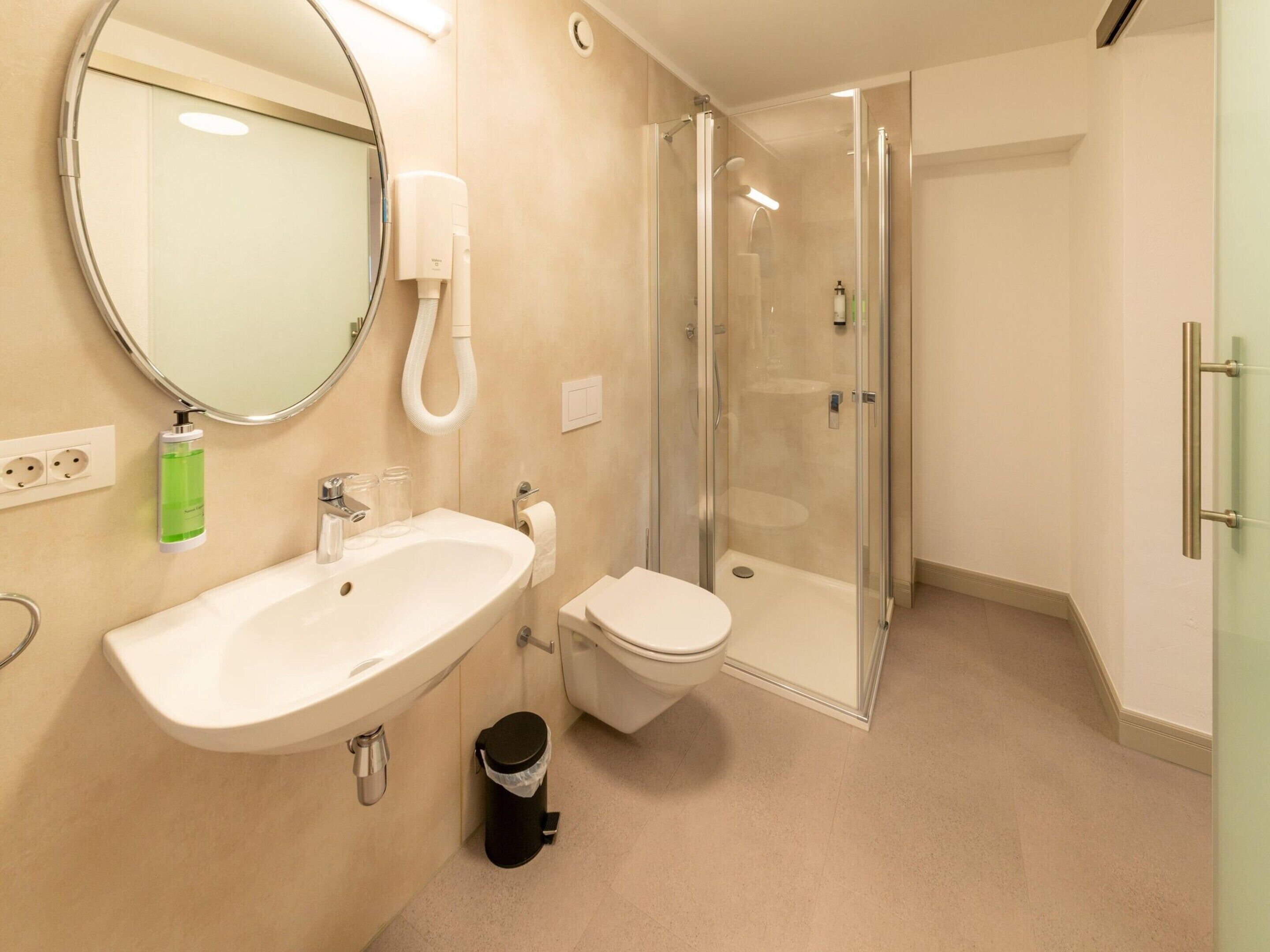 Ein modernes Badezimmer mit Waschbecken, Toilette und einer Duschkabine.