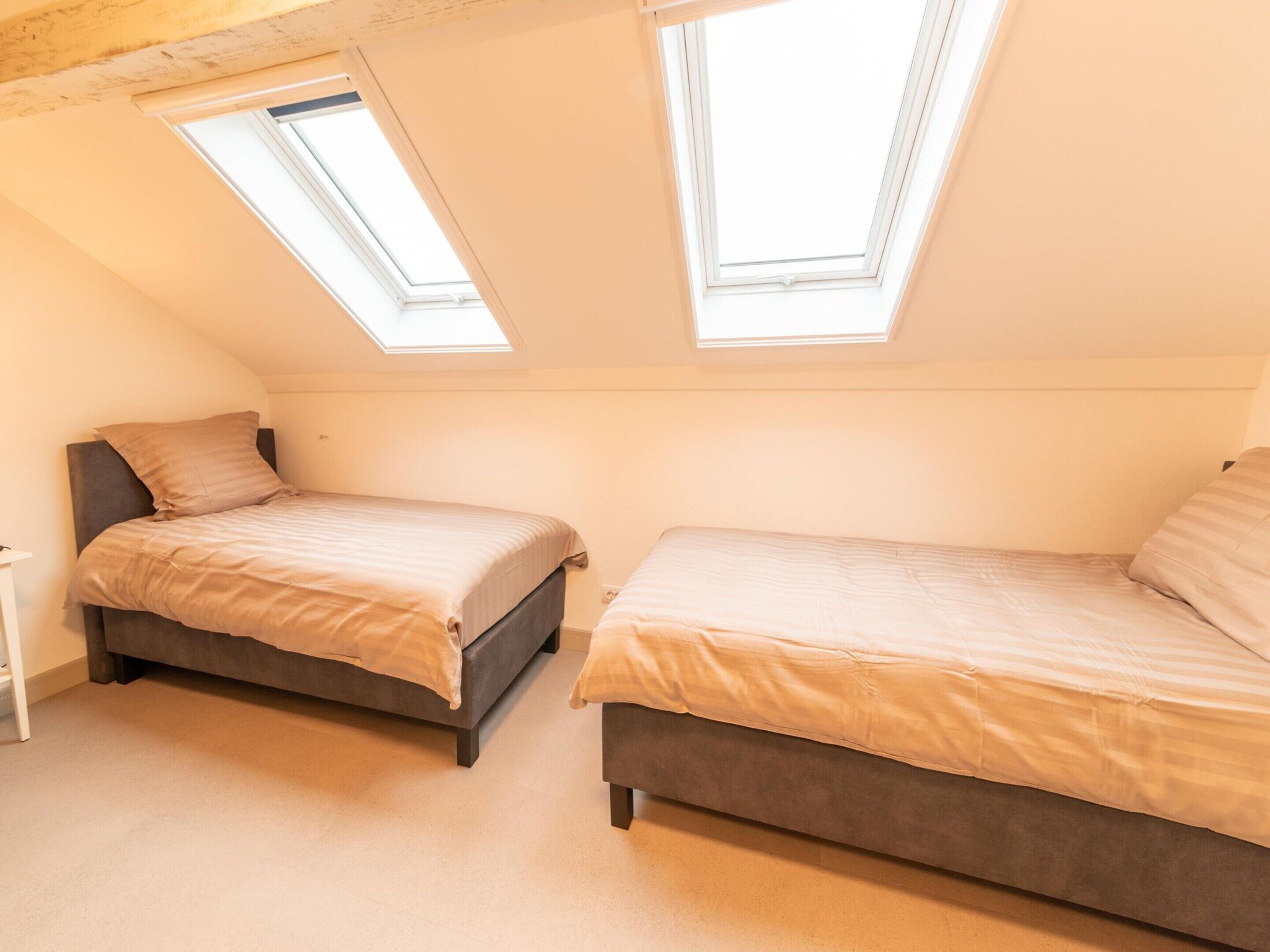 Ein Schlafzimmer mit zwei Betten, einem Oberlicht und einer schrägen Decke.