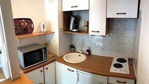 Una cocina compacta equipada con microondas, cafetera, pileta y cocina.