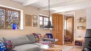 A cozy living room with a grey sofa, a round wicker side table, and a black lamp. - 5 Person Holiday Home in Nexo (Nexø)
