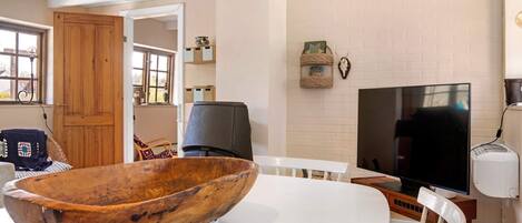 A modern living room with a large wooden bowl centerpiece, a flat-screen TV, and a rustic ceiling.