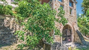 A stone building with a large arched entrance and a bicycle parked outside. - Villa Lucertole (Città di Castello)