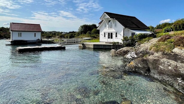 A white house with a tiled roof on a dock, clear water, and rocky shoreline. - 4 Star Holiday Home in Mosterhamn-by Traum (Bomlo)