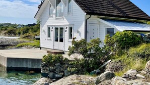 A white house with a dark roof, situated by a body of water with a dock. - 4 Star Holiday Home in Mosterhamn-by Traum (Bomlo)