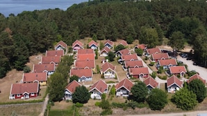 A residential area with houses having red roofs, surrounded by dense forest and a lake in the background. - Holiday Home Villa Pippilotta (Userin)
