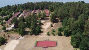 An aerial view of a residential area with houses, a basketball court, and a lake in the background. - Holiday Home Villa Pippilotta (Userin)